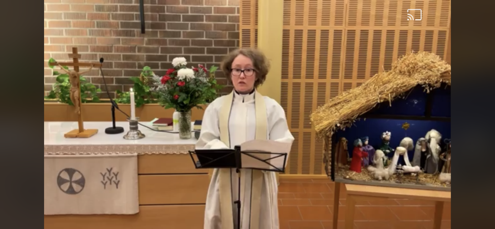 Prästen Emilia Kontunen står bredvid julkrubban i kyrksalen i Smedsby församlingsgård