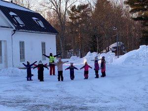 Barn sjunger och leker ute i snön med en ledare